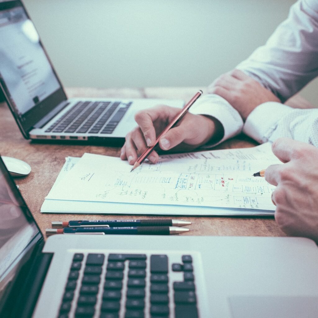 person holding pencil near laptop computer to talk about businesses, represent what a student will learnt as enrolled in bachelor of business administration